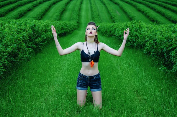 Βίκινγκ επιθετική μακιγιάζ κορίτσι cosplay σε ένα πράσινο χωράφι σιταριού. Γονατιστή, προσεύχεται στους αρχαίους θεούς. Παγανισμός, φεμινισμός, ανεξαρτησία, φυλή. — Φωτογραφία Αρχείου