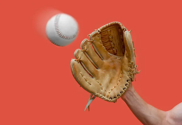 La mano en un guante de béisbol de cuero atrapa una bola blanca en desenfoque sobre un fondo rojo —  Fotos de Stock