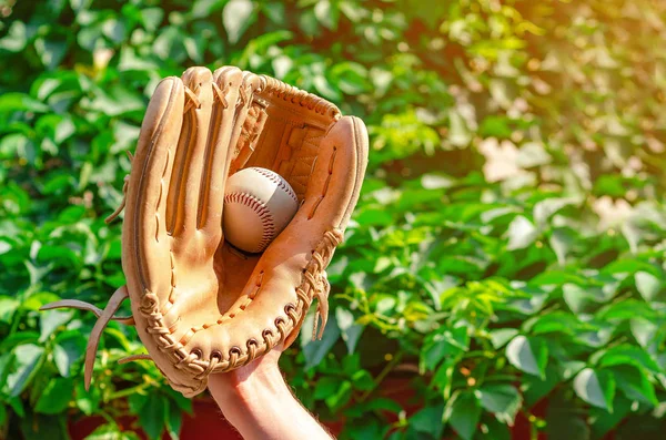 Mano maschile in un guanto di cuoio da baseball catturato una palla su una b verde — Foto Stock