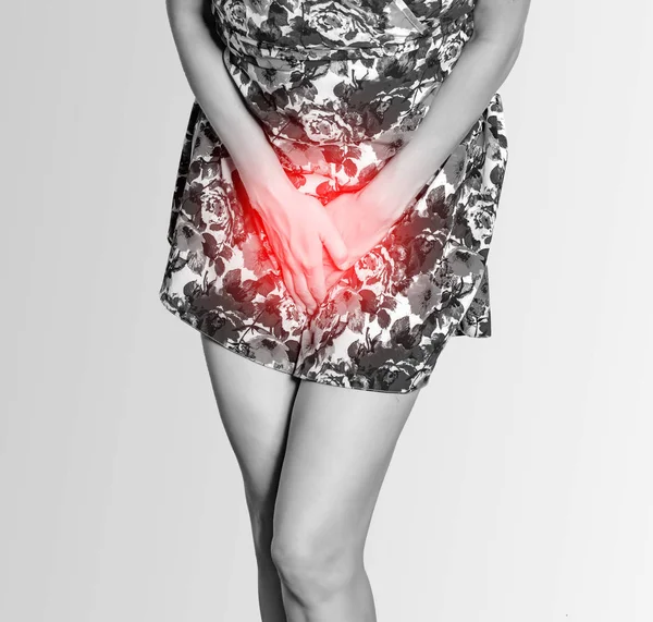 Woman in a colored dress presses her hands to her stomach, experiences pain, inconvenience, and urinary incontinence. Gynecological problems, women's health, uterus. Red zone of pain. — Stock Photo, Image