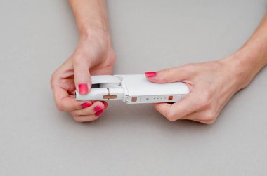 Kadının ellerinde elektronik sigara var. Ağızlığa bir sigara yerleştirin. Sigara, sağlık, mücadele, bağımlılık