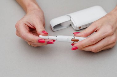 Kadının ellerinde elektronik sigara var. Ağızlığa bir sigara yerleştirin. Sigara, sağlık, mücadele, bağımlılık