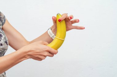 Kadın eli sarı bir muza prezervatif takıyor. Gösterim