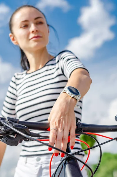 Radfahrerin, Porträt gegen den Himmel. Hand mit einer intelligenten Uhr — Stockfoto
