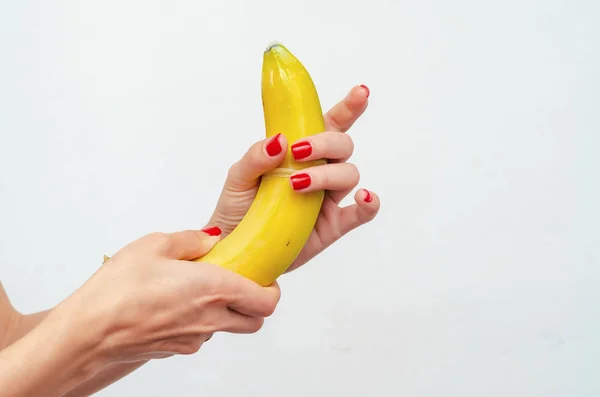 Female hands pull a condom on a yellow banana. Demonstration