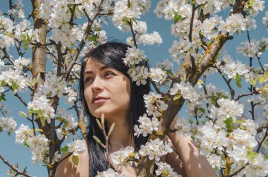 Beyaz çiçekli güzel esmer bir kızın portresi çiçek açan armut ağacı. Bahar, güzellik, kadın sağlığı konsepti.