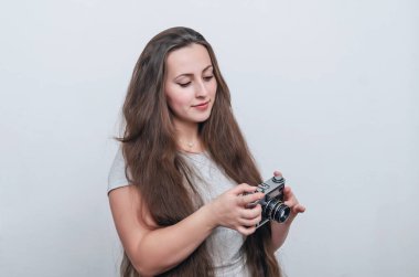 Uzun saçlı, kilolu bir kız elinde kamera tutuyor..