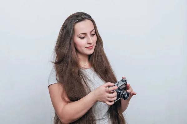 一头浓密的长发女孩双手拿着胶卷相机在大腿上 — 图库照片