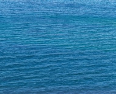 Mavi deniz suyunda küçük dalgalar. Doğa geçmişi, seyahat tatili.