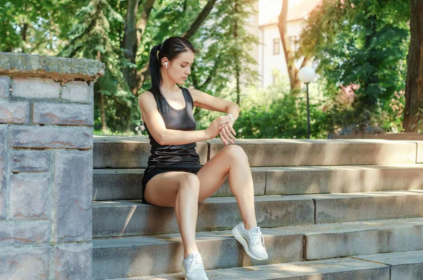 Chica Atlética Pantalones Cortos Camiseta Sentada Escaleras Piedra Mirando Reloj — Foto de Stock