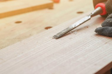 Marangoz tahtayı metal keskiyle işliyor.