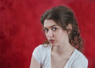 Kırmızı arka planda genç kıvırcık kızın portresi. Sakinleş..