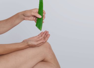 Kadın oturur ve deriyi iyileştirmek ve acıyı dindirmek için dizine aloe vera jeli sürer. Aloe Vera çeşitli hastalıkları tedavi etmek için kullanılır..
