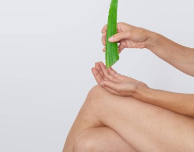 Kadın oturur ve deriyi iyileştirmek ve acıyı dindirmek için dizine aloe vera jeli sürer. Aloe Vera çeşitli hastalıkları tedavi etmek için kullanılır..