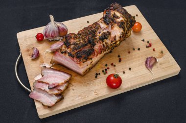 Kesilmiş domuz göbeği. Tahta üzerinde leziz domuz eti dilimleri taze sarımsak karanfilleri, kiraz domatesleri ve renkli biberlerle birlikte. Siyah arkaplan.