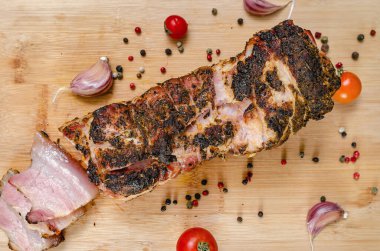 Kesilmiş domuz göbeği. Tahta üzerinde leziz domuz eti dilimleri taze sarımsak karanfilleri, kiraz domatesleri ve renkli biberlerle birlikte. Siyah arka plan. Üst görünüm.