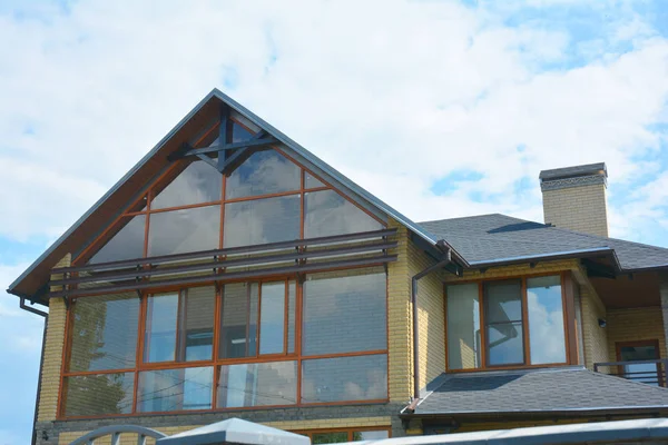 Modern house attic construction with roof guttering and panoramic mansard, attic skylight window.  Attic skylight glass wall.