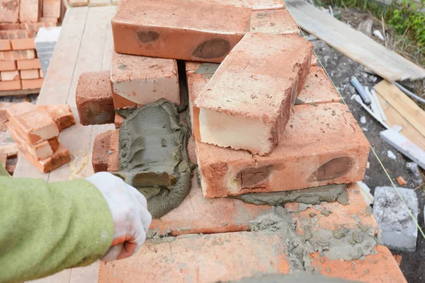 Professional construction worker laying bricks on house construction site.