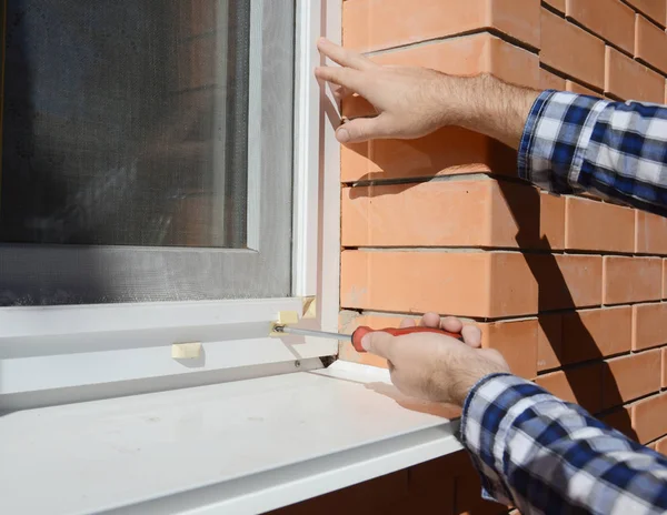 安装在房屋窗户上的蚊子丝网的修理工 — 图库照片