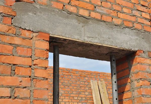 Beton kapı lentosu üzerinde yükleme metal sahipleri ile. Beton kapı lentosu üzerinde tuğla bitmemiş ev yapımı. 