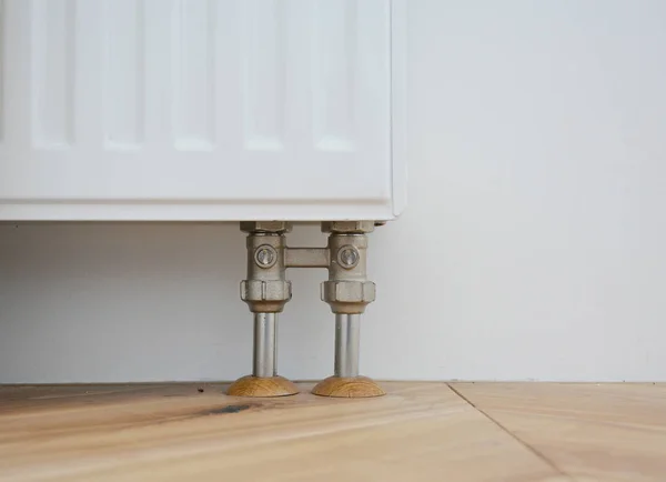 Radiator pipe covers sleeves. Install radiator for heating system with hiding pipes in the wooden floor. Radiator pipe sleeves.