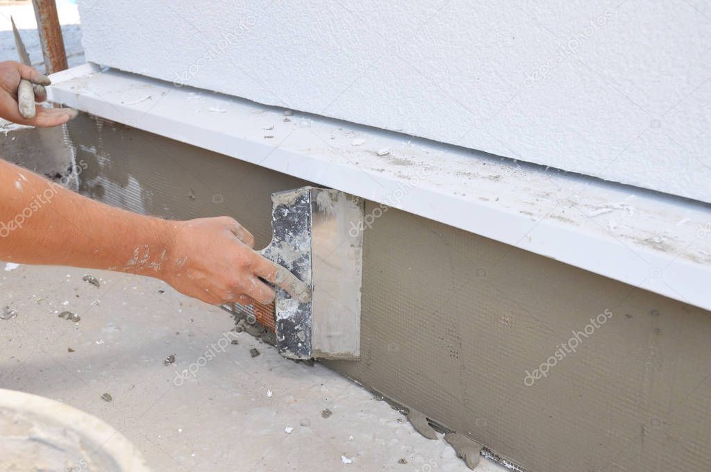 Contractor plastering, repair,  stucco house foundation after styrofoam insulation.  