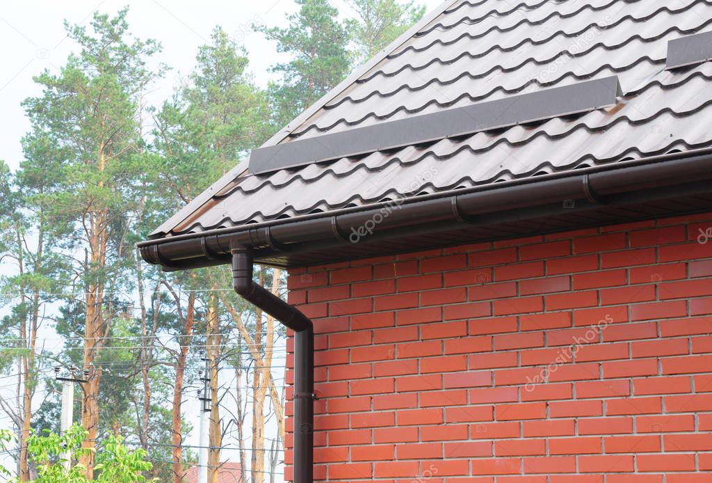 Roof gutter with metal snow board for snow protection. Metal roofing construction with guttering.