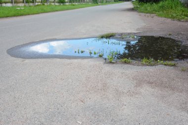 Su birikintileri asfalt yolda. Pot delik veya çukur bir kırık kırık asfalt kaplama görüntüsünü.
