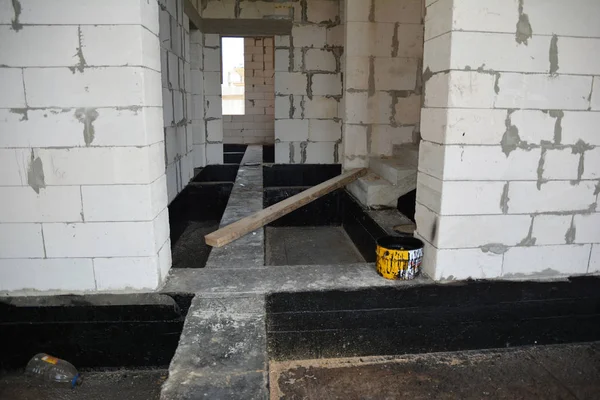 Foundation bitumen waterproofing. Building house construction with waterproofing spray-on tar. Construction techniques for spraying waterproofing basements and foundations.