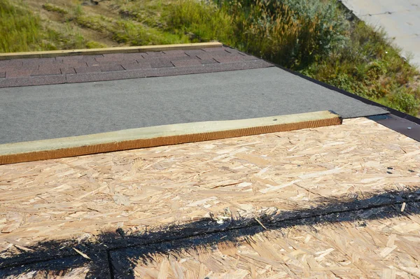 Asphalt shingles installing on house construction roof with all details. Roofing construction top view. Installing roof tiles with waterproofing membrane and bitumen spray.