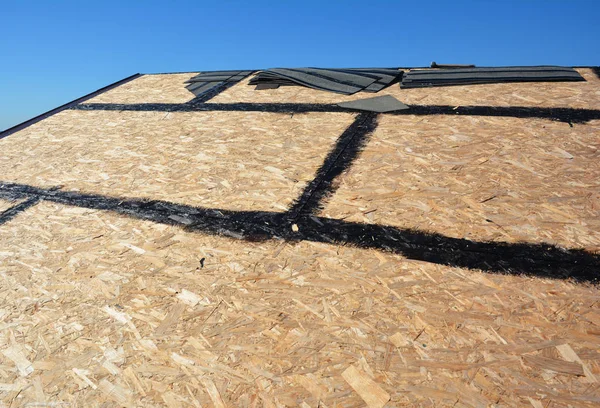 Roofing preparation asphalt shingles installing on house construction wooden roof with bitumen spray. Roofing construction. Installing bitumen roof shingle.