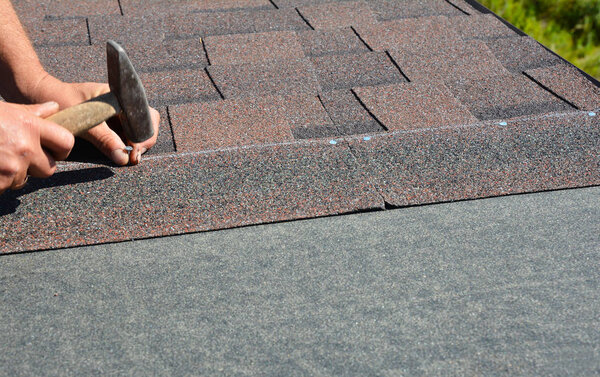 Roofing contractor installing roof tiles, asphalt shingles with copy space.