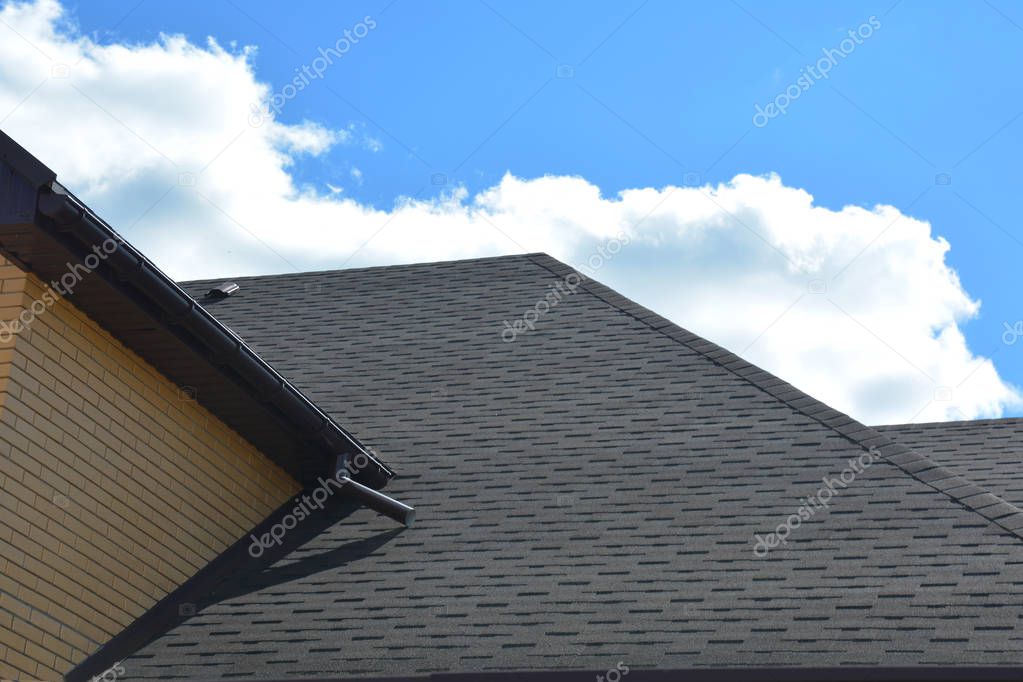 Wateproofing roof problem area with asphalt shingles and rain gutter. Asphalt shingles roofing construction.