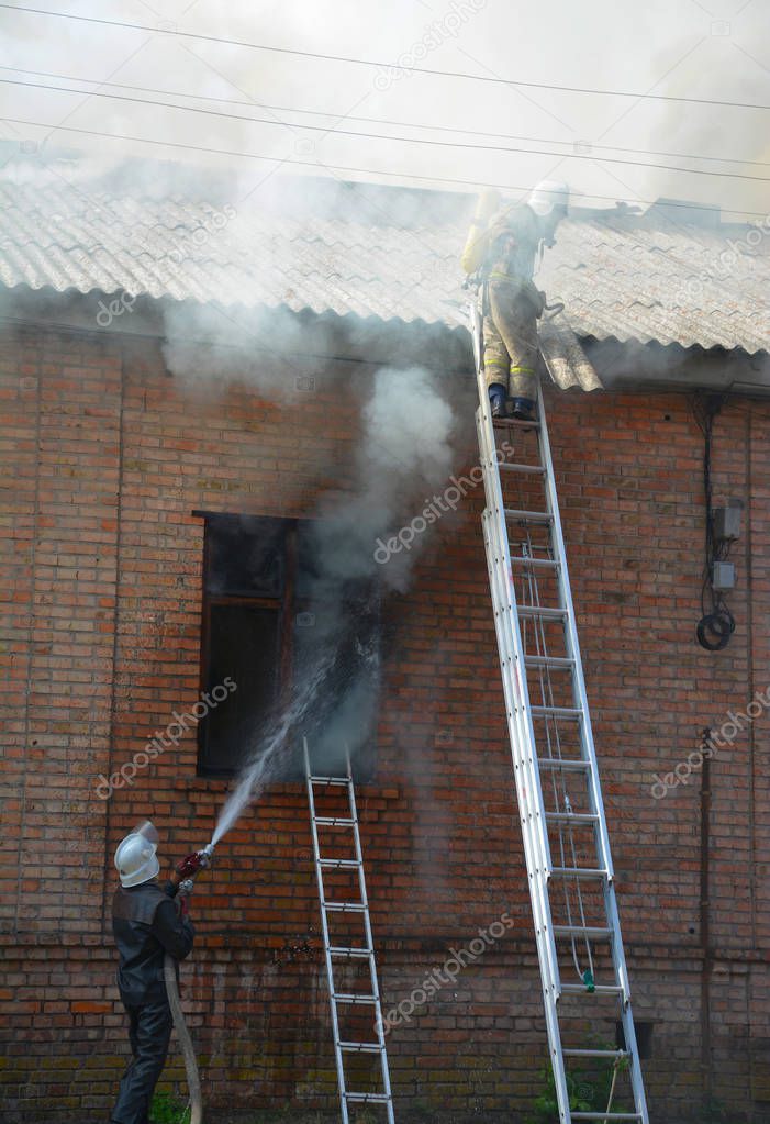 Burning house and firefighters on the ladders.