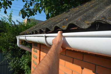 Roofer repair and renovate roof gutter on old brick  house asbestos roof. clipart