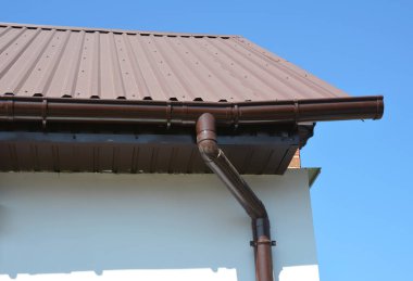 House metal roof corner with plastic rain gutter pipeline system. clipart