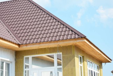 Taş duvar duvar izolasyonu ile metal çatı inşaat. Bitmemiş recessed panoları yükleme.