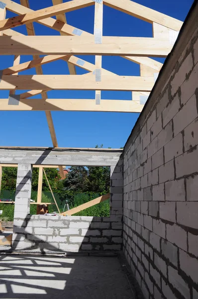 House construction with roof beams, trusses, wooden frame beams on rooftop.
