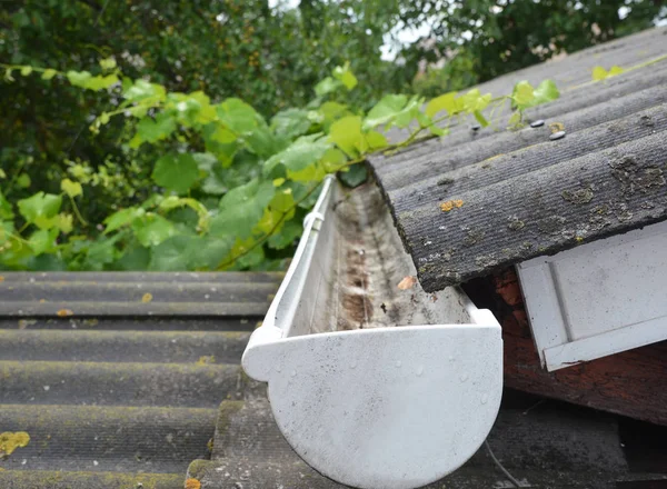 Rain gutter and asbestos roof. Close up on plastic roof gutter.