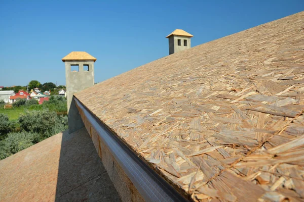 Roofing construction with wooden boards before laying asphalt shingles on house roof.