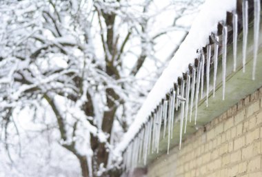 Buz sarkıtları evin çatı kar yağışı ile ve arka plan bulanık. Güzel kış manzarası. Buz sarkıtları evi.