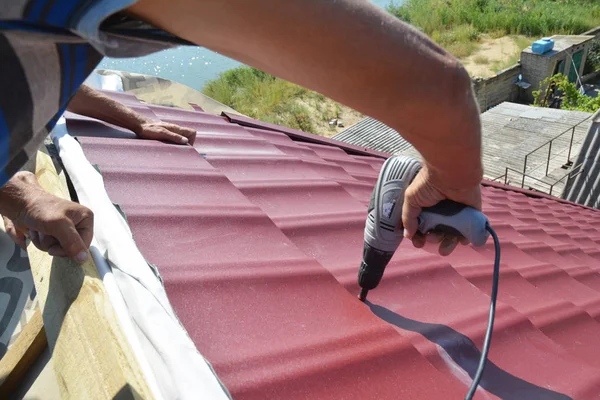 Roofing contractors installing metal roof tile for roof repair. Roofing construction.