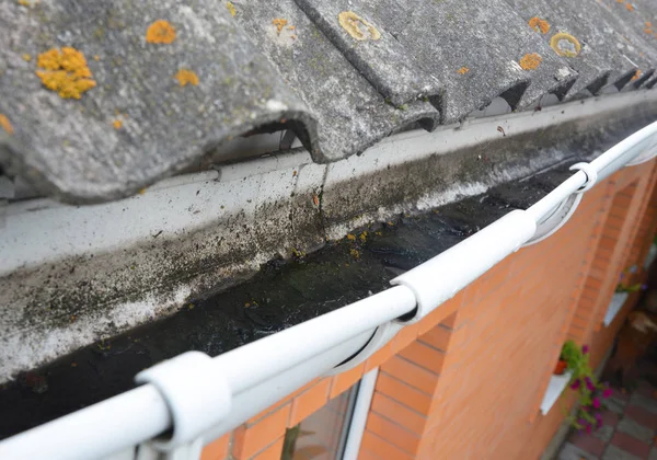 Dirt in roof gutter. House asbestos roof with rain gutter and dirt need to clean