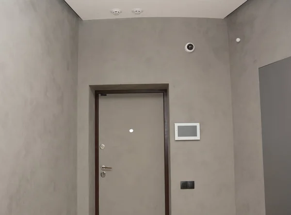 Modern house entrance metal door interior with  smart house system, security camera, smoke alarms and fire detection.