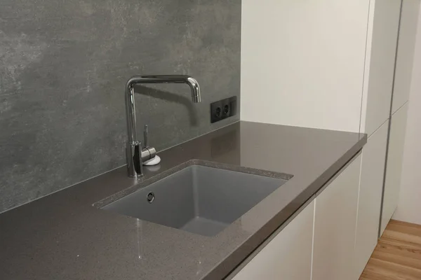 Black kitchen sink and Tap water in the kitchen. Modern kitchen metal faucet and  kitchen sink.