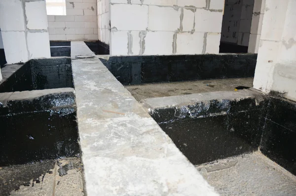 Foundation bitumen waterproofing. Building house construction with waterproofing spray-on tar.