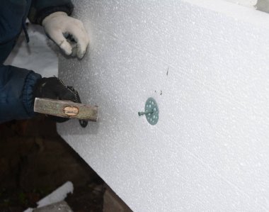 Builder yüklenici sert köpük yalıtım levhası köpük yalıtım tutmak için plastik çivi çekiç ile yükleme.