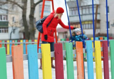  Kışın oyun alanında küçük çocuğu olan genç bir anne. Kasıtlı hareket bulanıklığı fotoğrafı.