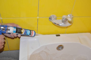  Silikon Banyo Caulk ile banyo tüpü kurulum, sarı karo banyoda su musluğu. Yeni banyo tüpü ile banyo tamir. Caulking Gun ile Silikon Bir Banyo