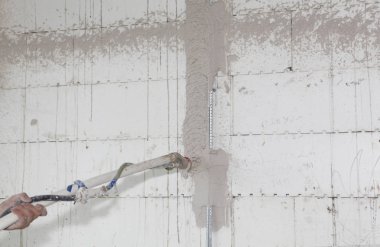 Oluşturucu elinde otomatik çimento duvar screeding alçı makine tutun. Ev sıva duvarları için sprey sıva makinesi ile sıva duvar. 